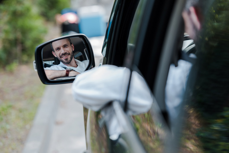 Man smiling in mirror on car