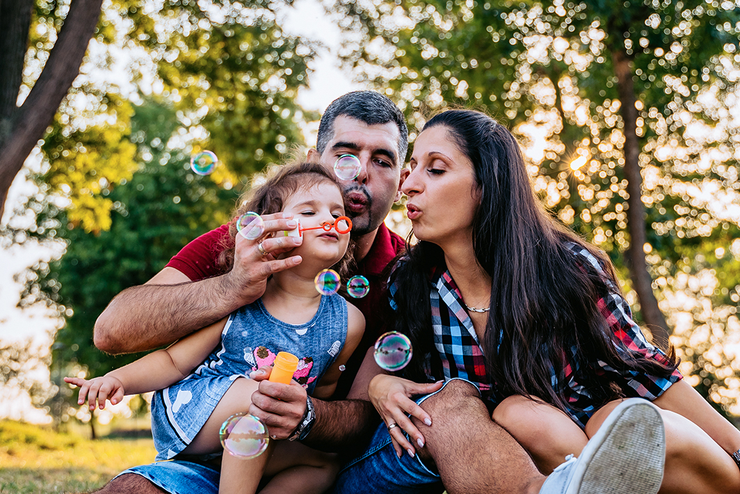 Family blowing bubbles in a park
