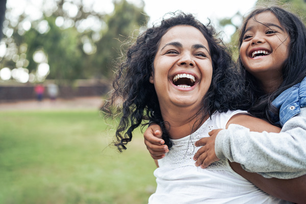 Happy mom with daughter outside.