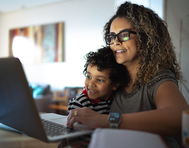 Woman looking at retirement accounts on laptop with little boy